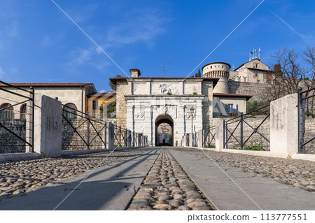 Ground-level perspective along cobbled pathway leading to Brescia castle 113777551
