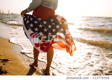 View from the back young brunette female person holding national American flag. 113778308