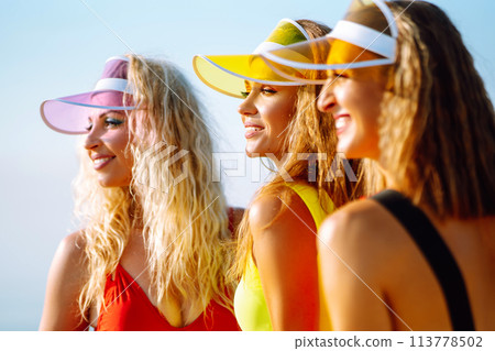 Three young woman - dancer dancing in bright swimsuits on the beach. Sport, fitness, active life. 113778502