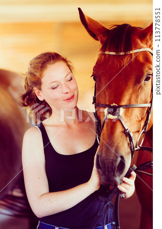 Woman hugging brown horse in stable Woman hugging brown horse in stable 113778551