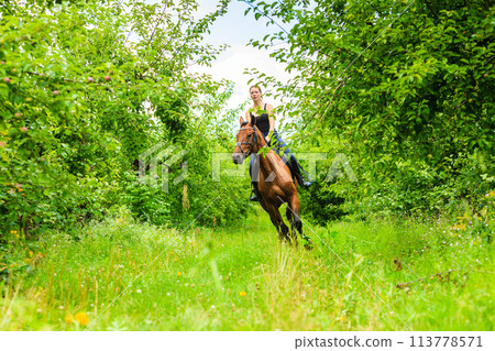 Young woman ridding on a horse Young woman ridding on a horse 113778571