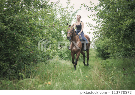 Young woman ridding on a horse Young woman ridding on a horse 113778572