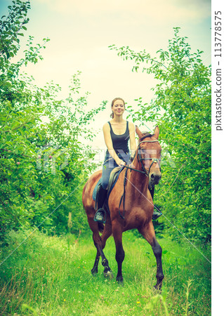 Young woman ridding on a horse 113778575