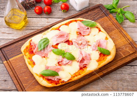 Traditional italian pizza with ham mozzarella and  basil 113778607