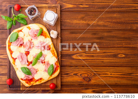 Traditional italian pizza with ham mozzarella and  basil 113778610