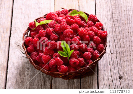 Raspberry in a basket .on wooden background Raspberry in a basket .on wooden background 113778723