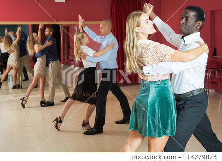 Positive adult couples dancing tango together in modern studio 113779023