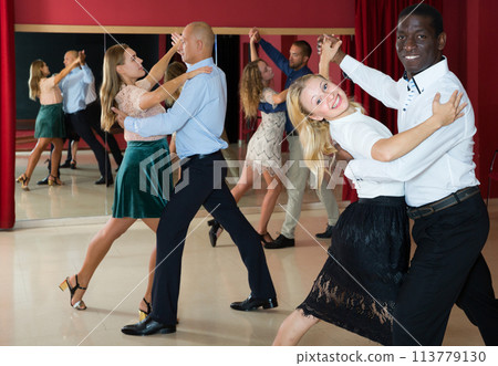 Positive adult couples dancing tango together in modern studio 113779130