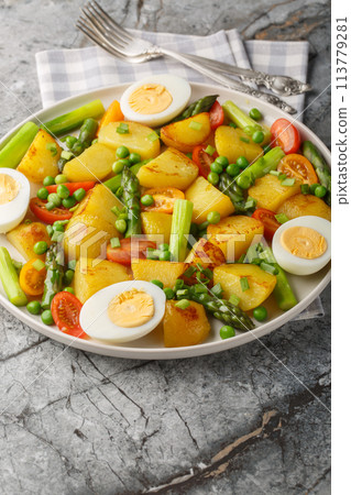 Summer salad with potatoes, green peas, asparagus, boiled egg and tomato closeup on the plate. Vertical Summer salad with potatoes, green peas, asparagus, boiled egg and tomato closeup on the plate. Vertical 113779281