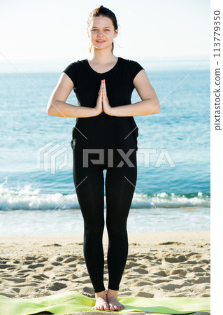 Smiling adult woman in black T-shirt is staying and practicing asana 113779350