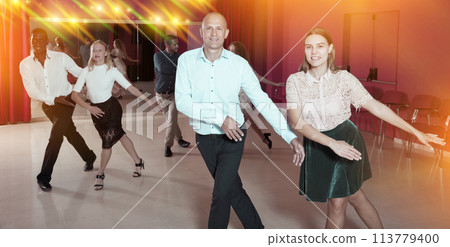 Active smiling people practicing lindy hop movements in dance class 113779400