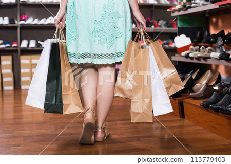 Female customer with bags of purchases is walking 113779403