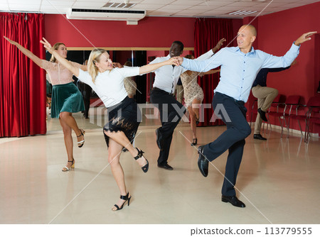 Young positive people dancing twist in pairs at dance hall together 113779555