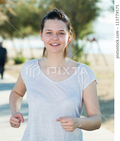 Girl in white T-shirt is jogging 113779575