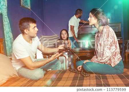 Young adults inspecting wooden rosary in escape room Young adults inspecting wooden rosary in escape room 113779599