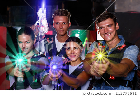 Young friends posing with colored laser guns in dark labyrinth Young friends posing with colored laser guns in dark labyrinth 113779681