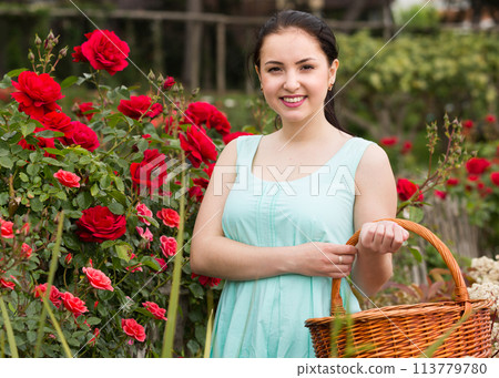 portrait of young female holding a basket near roses in outdoors portrait of young female holding a basket near roses in outdoors 113779780