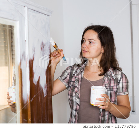 Female designer is repairs and coloring old wardrobe in modern color Female designer is repairs and coloring old wardrobe in modern color 113779786