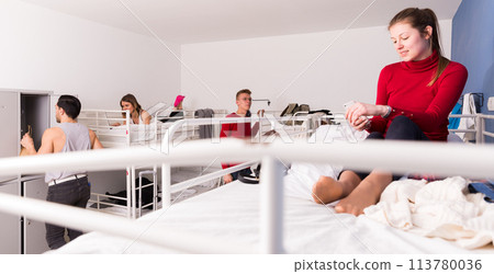 Girl with phone on bed in hostel 113780036