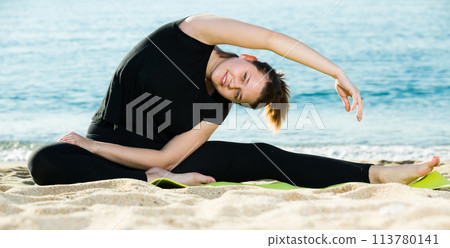 Smiling adult female in black T-shirt is practicing asana Smiling adult female in black T-shirt is practicing asana 113780141