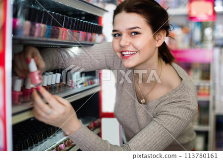 Smiling woman customer deciding on nail polish Smiling woman customer deciding on nail polish 113780161