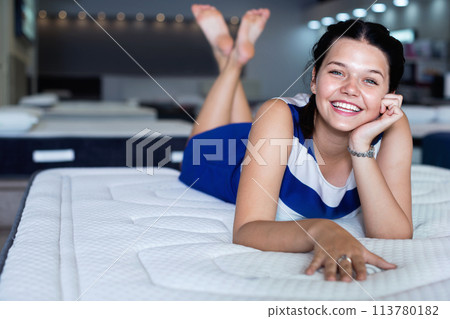Female is lying on mattress for testing it in the store. 113780182