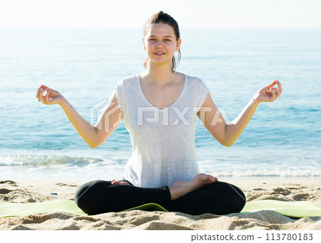 Female 20-30 years old in white T-shirt is sitting and doing meditation 113780183