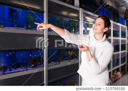 Girl in aquarium shop points to colored fish Girl in aquarium shop points to colored fish 113780188