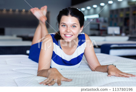 Female is lying on mattress for testing it in the store. Female is lying on mattress for testing it in the store. 113780196