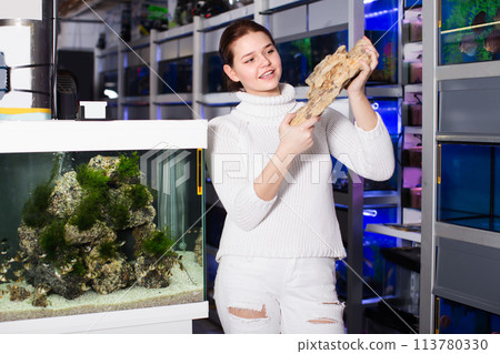 Smiling child is holding large yellow-brown sandstone for aquarium decoration 113780330