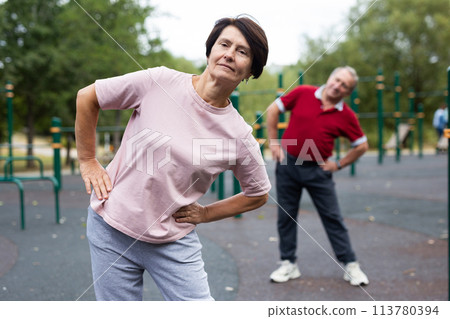 Sports pensioners do a warm-up on outdoor sports ground 113780394