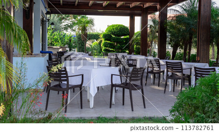 Cozy Greek restaurant with tables covered with white tablecloths.  113782761