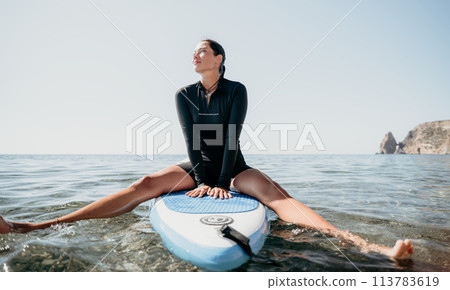 Woman sup yoga. Happy sporty woman practising yoga pilates on paddle sup surfboard. Female stretching doing workout on sea water. Modern individual female hipster outdoor summer sport activity. 113783619