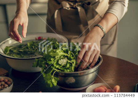 person preparing a bowl of fresh greens, emphasizing the farm-to-table connection and the beauty of organic ingredients 113784449