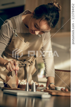 moment of concentration in a kitchen, showcasing the step-by-step process involved in creating perfectly decorated cupcakes 113784452