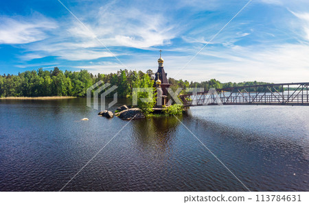Aerial top view to wooden Church of St. Apostle Andrew First-Called on Vuoksa River with bridge. Temple on small island near village Vasilevo, Melnikovo, Priozersky District Leningrad region. Russia 113784631
