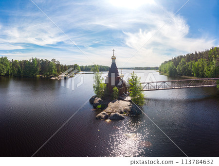 Aerial top view to wooden Church of St. Apostle Andrew First-Called on Vuoksa River with bridge. Temple on small island near village Vasilevo, Melnikovo, Priozersky District Leningrad region. Russia 113784632
