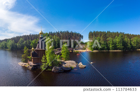 Aerial top view to wooden Church of St. Apostle Andrew First-Called on Vuoksa River with bridge. Temple on small island near village Vasilevo, Melnikovo, Priozersky District Leningrad region. Russia 113784633