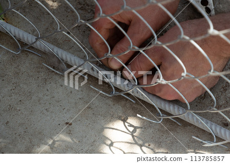 fastening the bottom of the fence made of galvanized rectangular mesh fastening the bottom of the fence made of galvanized rectangular mesh 113785857