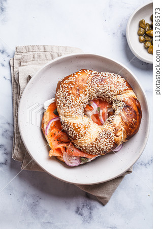 Breakfast bagel with salmon, cream cheese, capers and onions, white background. Breakfast bagel with salmon, cream cheese, capers and onions, white background. 113786573