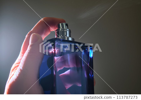 Perfume spray in a violet bottle on a dark background. Perfume spray in a violet bottle on a dark background. 113787273