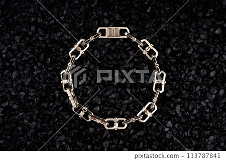 Gold bracelet on a background of black volcanic stones. 113787841
