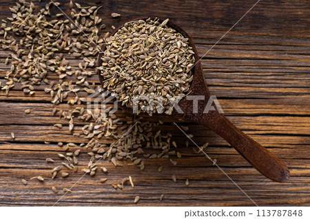Aromatic dry anise seeds on a dark wood background. Aromatic dry anise seeds on a dark wood background. 113787848