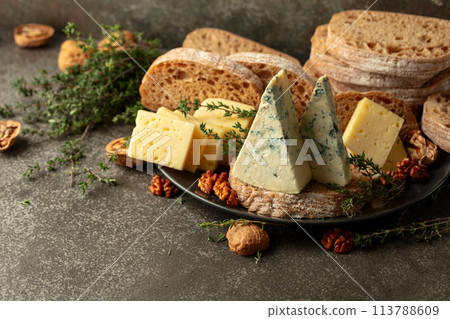 Cheese, bread, walnuts, and thyme on a stone kitchen table. 113788609