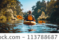 Kayaking on a serene river, amidst a green forest, under a clear blue sky, captured mid-action 113788687