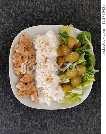 Homemade grilled chicken with green salad, rice pilaf and cucumber pickles served on a white plate Homemade grilled chicken with green salad, rice pilaf and cucumber pickles served on a white plate 113789426