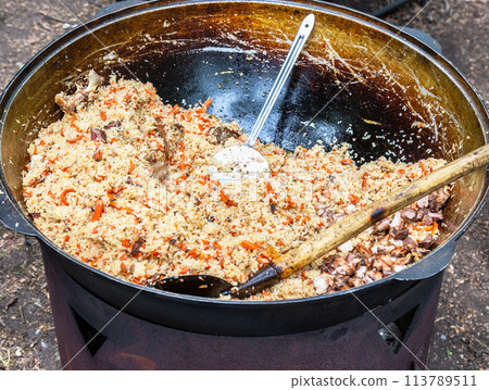 Appetizing traditional Uzbek pilaf in a large cauldron Appetizing traditional Uzbek pilaf in a large cauldron 113789511
