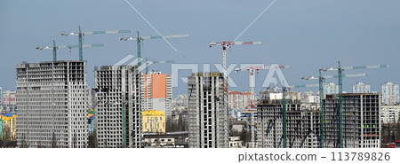 Kyiv, Ukraine April 7, 2022: tower construction cranes build high-rise buildings in Kyiv against the blue sky Kyiv, Ukraine April 7, 2022: tower construction cranes build high-rise buildings in Kyiv against the blue sky 113789826