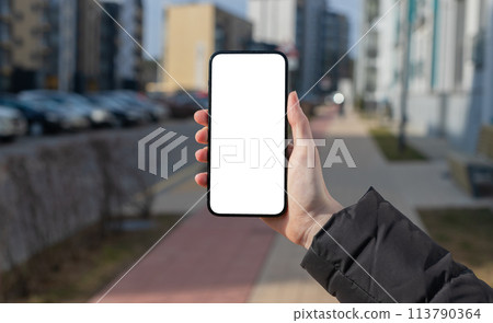 Urban smartphone use, person holding mobile phone with touchscreen, cityscape mock up. Digital 113790364