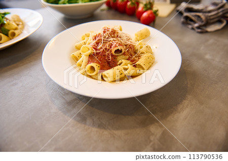 Italian pasta penne with tomato sauce and basil on white plate on marble background 113790536